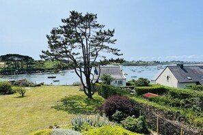 A coastal property with a large tree, a grassy lawn, and a view of boats on the water. - Villa Monrepos Portsall (Ploudalmézeau - Portsall)
