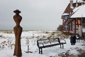 A wooden sculpture, a bench, and a building with a red and white facade. - Holiday apartment with 2 bedrooms (Zingst)