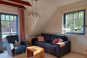 Ein gemütliches Wohnzimmer mit einer Couch, einem Sessel und einem Couchtisch.
