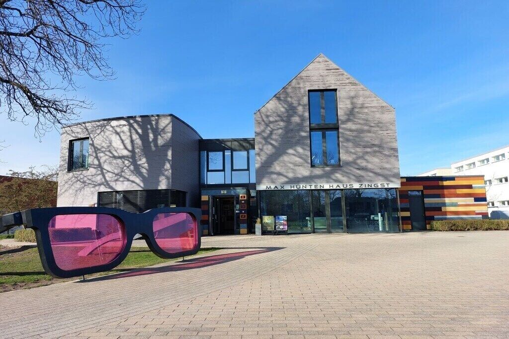 Un edificio con un diseño arquitectónico moderno, que destaca por su entrada principal y un cartel que reza 'MAX HUNTEN HAUS ZINGST'.