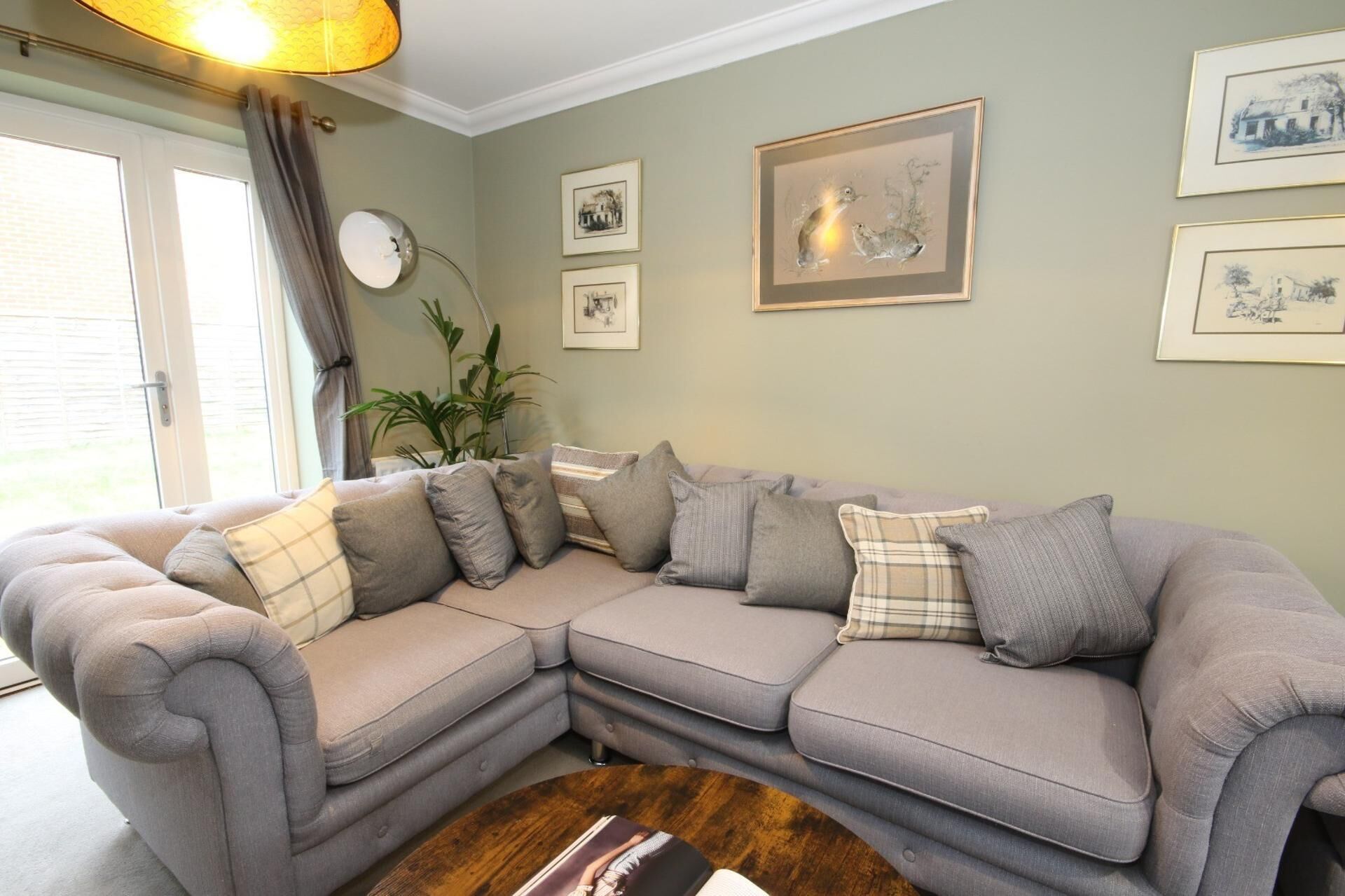 A living room with a grey sectional sofa, a wooden coffee table, and framed artwork on the walls.