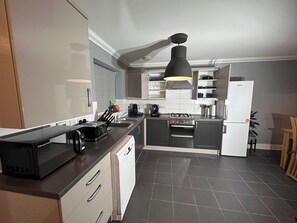A modern kitchen with a built-in dishwasher, a gas stove, and a refrigerator. - 4 Bedroom Ipswich Home - Sleeps 8 - Free Parking (Ipswich)