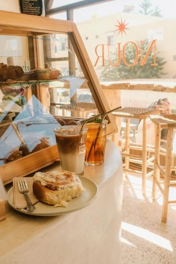 A café counter with a pastry, a drink, and a menu.