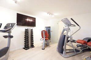 Un gimnasio con equipo de cardio, máquinas de pesas y una pantalla de televisión.