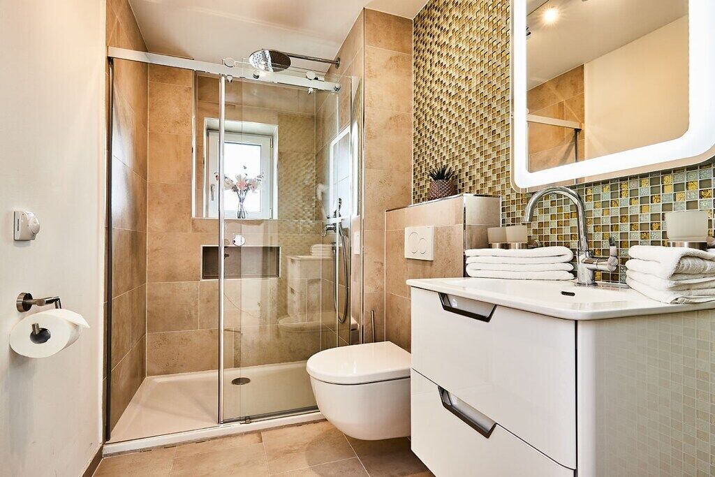 Een moderne badkamer met een douchecabine van glas, een toilet en een wastafel met spiegel.