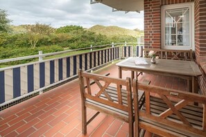 A balcony with a brick floor, a white railing, and a table with chairs. - Holiday apartment in Juist with swimming pool (Juist)