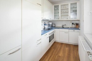 A compact kitchen with white cabinetry, a blue countertop, and a built-in oven. - Holiday apartment in Juist with swimming pool (Juist)