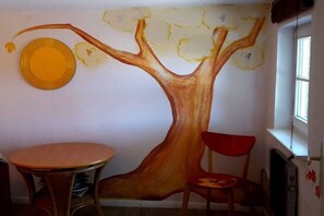 A wall with a tree mural, a round table, and a red chair. - Holiday apartment with 3 bedrooms (Niesgrau)