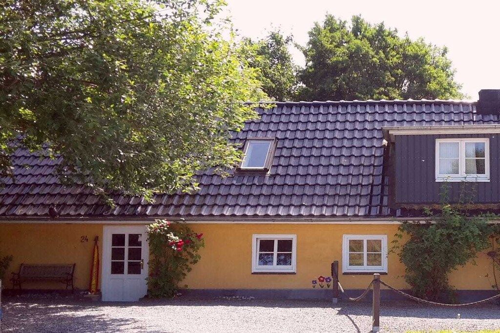 A two-story building with a tiled roof, a door, and windows.