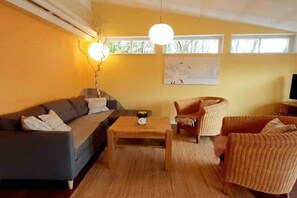 Ein Wohnzimmer mit einer Couch, Sesseln, einem Couchtisch und einem Gemälde an der Wand.