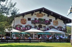 A traditional building with a balcony, outdoor seating, and flower arrangements. - Holiday apartment with 1 bedroom (Inzell)
