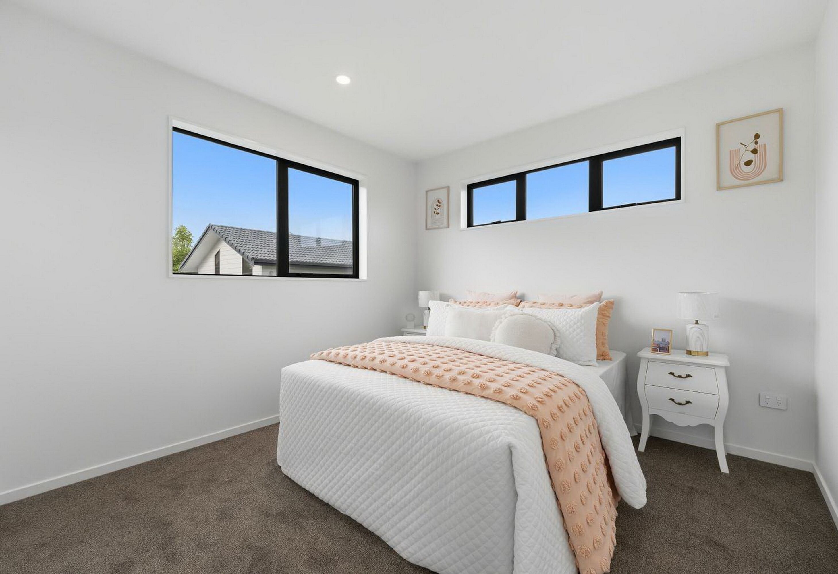 A bedroom with a bed, two bedside tables, a nightstand, and two windows.