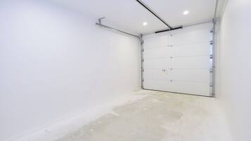 A clean, empty garage with a white door and a ceiling-mounted light fixture.
