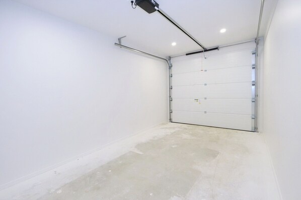 A clean, empty garage with a white door and a ceiling-mounted light fixture.