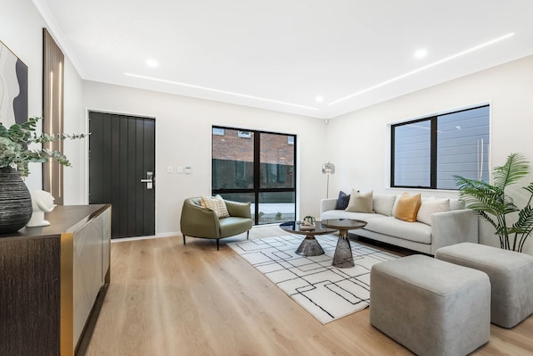 A modern living room with a sofa, armchairs, a coffee table, and a rug.