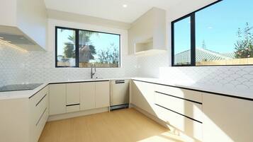 A modern kitchen with white cabinetry, a large window, and a view of the outdoors.