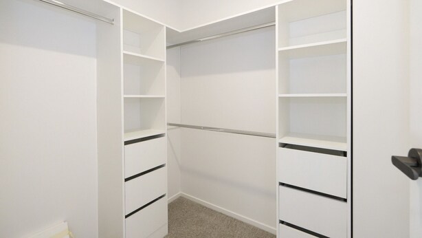 A walk-in closet with open doors, revealing multiple shelves and drawers.