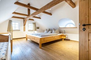 A bedroom with a wooden bed, a window with curtains, and a skylight. - Holiday home with 1 bedroom (Großschönau)