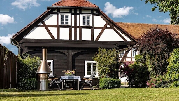 A traditional half-timbered house with a chimney, a table with chairs, and a garden. - Holiday home with 1 bedroom (Großschönau)