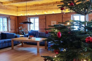 A cozy cabin interior with a wooden ceiling, a Christmas tree, and blue-striped sofas. - Holiday home with 1 bedroom (Großschönau)