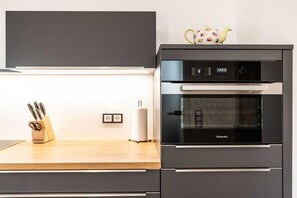 Eine moderne Küche mit eingebautem Backofen, einem Messerblock und einer Steckdose.