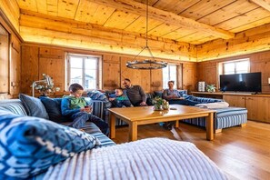 Ein gemütliches Holzinterieur mit einer Sofagarnitur, einem Couchtisch und einem Fernseher.