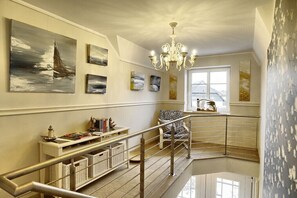 A spacious interior with a staircase, a chandelier, and artwork on the walls. - Holiday apartment with 1 bedroom (Zingst)