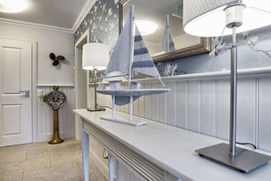 A bathroom with a white vanity, a round mirror, a wall-mounted fan, and a decorative sailboat model. - Holiday apartment with 1 bedroom (Zingst)