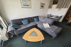 Una sala moderna con un sofá seccional, una mesita de centro y un comedor con mesa y sillas.