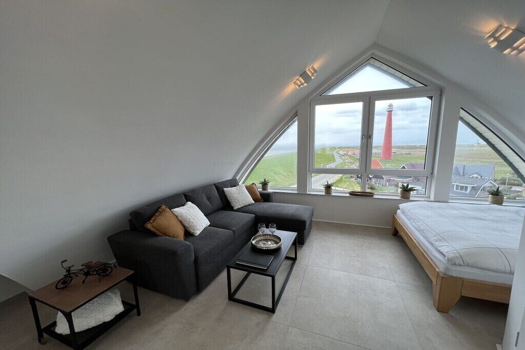 A modern loft bedroom with a large skylight, a bed, a sofa, and a coffee table.