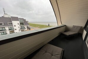 A balcony with a view of a beach and buildings. - Apartment in Huisduinen with swimming pool (Huisduinen)