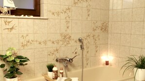 Ein Badezimmer mit Badewanne, Dusche und einem Fenster, das mit einer Bootsdekoration versehen ist.