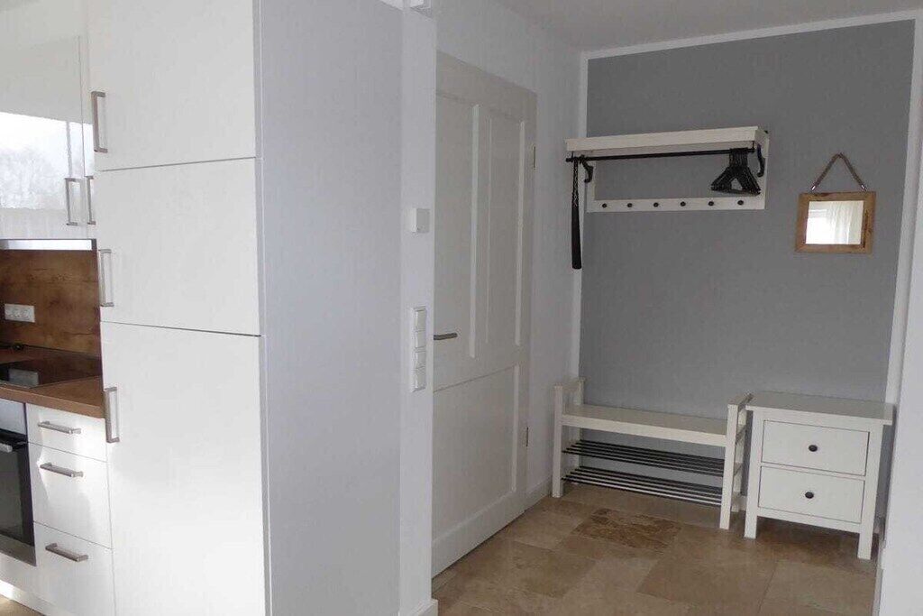 Eine kompakte Küche mit weißen Schränken, einem eingebauten Backofen und einer kleinen Arbeitsfläche.