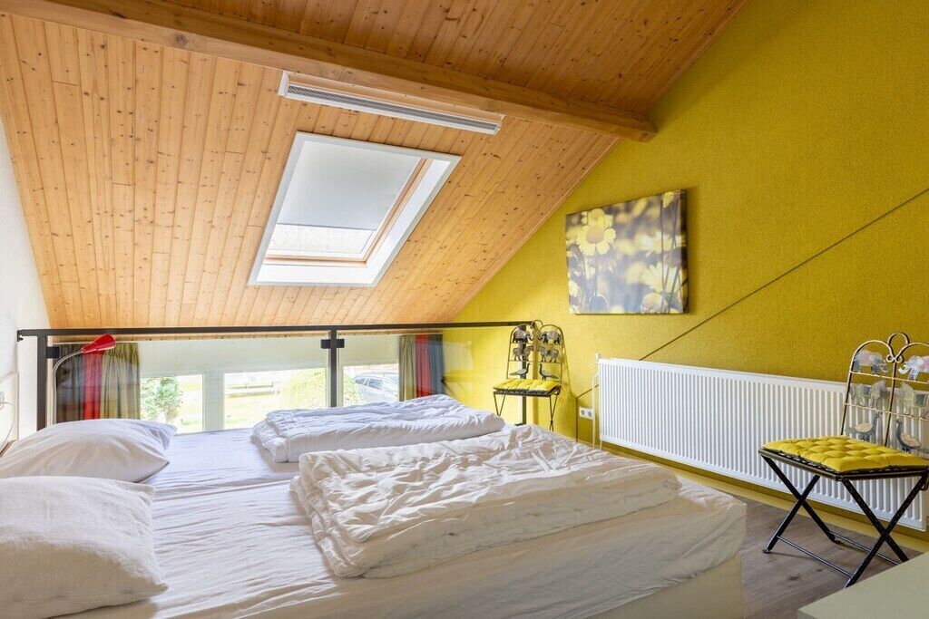 A room with two beds, a skylight, a radiator, and a yellow wall.