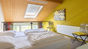 A room with two beds, a skylight, a radiator, and a yellow wall. - De Woeste Hoeve No. 90 (Zoutelande)