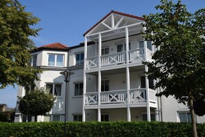 Un immeuble à plusieurs étages, doté de balcons, d’un toit rouge et de murs blancs.
