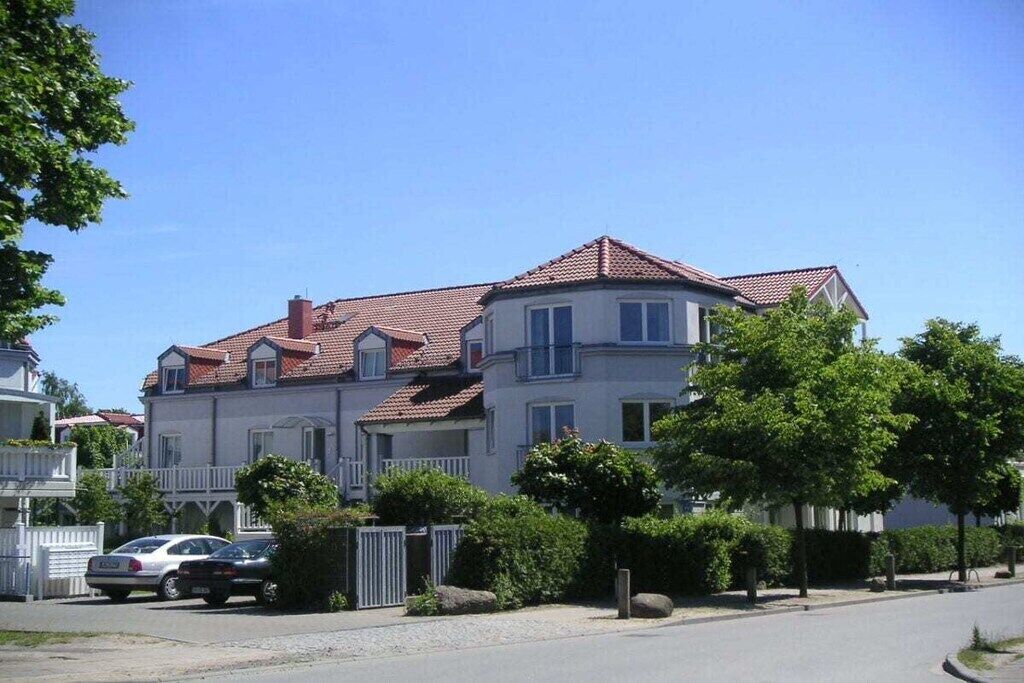 Ein zweistöckiges Wohnhaus mit rotem Ziegeldach, zahlreichen Fenstern und einem ehrverfüllten Einfahrtsbereich.
