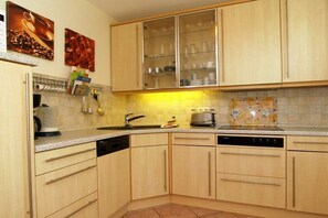 A kitchen with wooden cabinets, a dishwasher, a coffee machine, and a toaster. - "Am Stadtwald" in Kühlungsborn (Kühlungsborn)