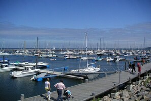 A marina with multiple boats docked, a wooden pier, and people walking. - "Am Stadtwald" in Kühlungsborn (Kühlungsborn)