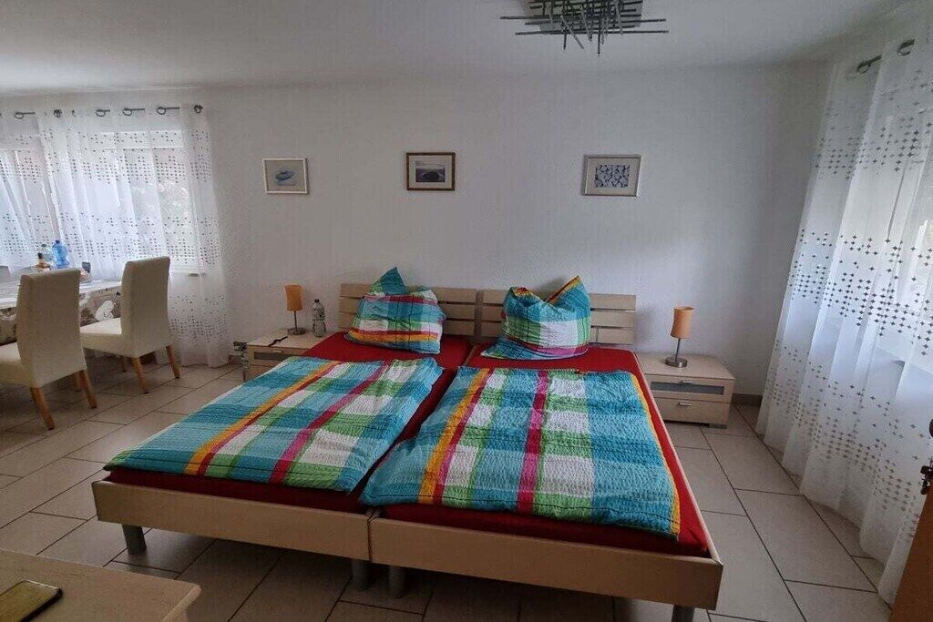 Un dormitorio con una cama, dos mesitas de noche, una silla y cortinas.