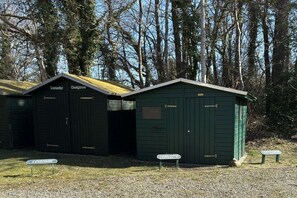 Une rangée de cabanes en bois peintes en vert, chacune portant une enseigne indiquant un nom, comme « Sommerlo » ou « Charlotte ».