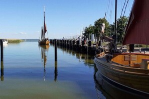 A calm waterfront with boats docked at a pier, clear skies, and a distant shoreline. - Holiday apartment with 1 bedroom (Born am Darß)