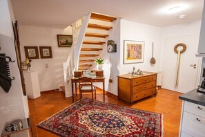 Een kamer met een houten trap, een bureau met stoel, een kast, een vloerkleed en een deur met sleutel.