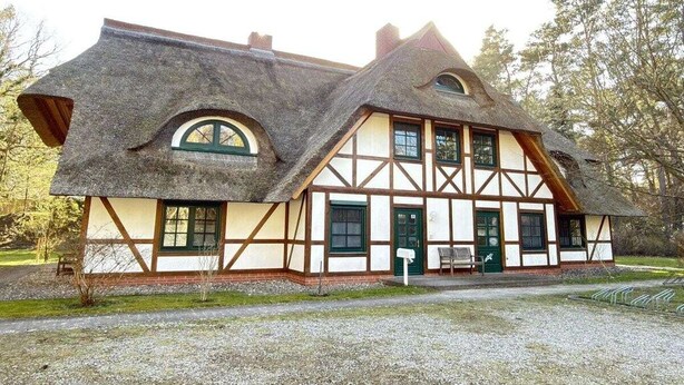 Une maison traditionnelle à colombages, dotée d’un toit à forte pente, de nombreuses fenêtres et d’une entrée principale.