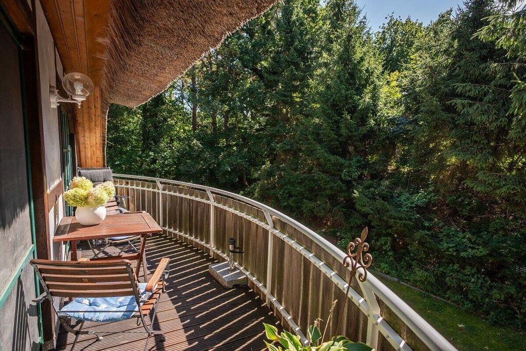 Une terrasse en bois avec une table et des chaises, donnant sur une zone boisée.