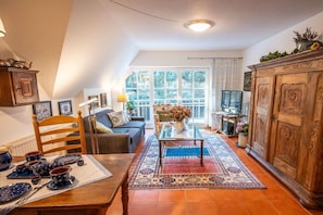 Een gezellige woonkamer met een bank, salontafel en een eettafel, gedekt met borden en bekers.