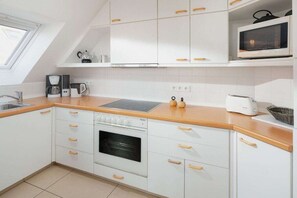 A modern kitchen with white cabinets, a built-in oven, a microwave, and a coffee maker. - Holiday apartment in Juist with swimming pool (Juist)