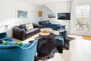 A modern living room with a sofa, armchairs, a coffee table, and a television. - Holiday apartment in Juist with swimming pool (Juist)