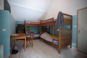 Ein Zimmer mit Etagenbetten, einem Schreibtisch, einem Stuhl und einem Heizkörper.