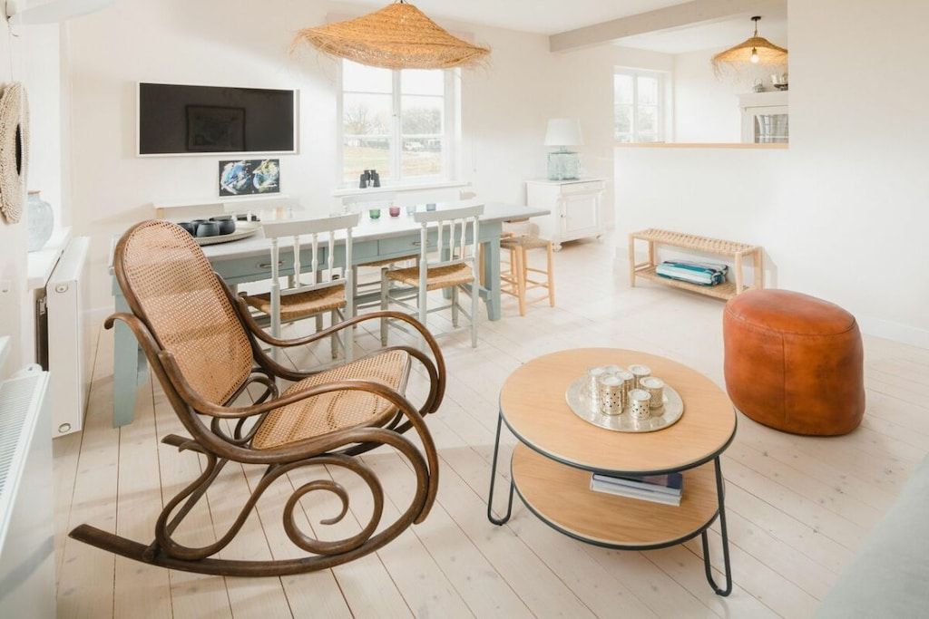 A modern living room with a dining area, a rocking chair, a round coffee table, and a sofa.